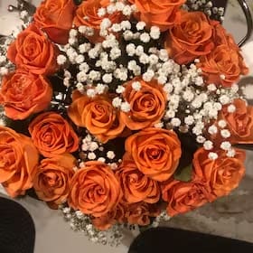 A bouquet of orange roses with white flowers.